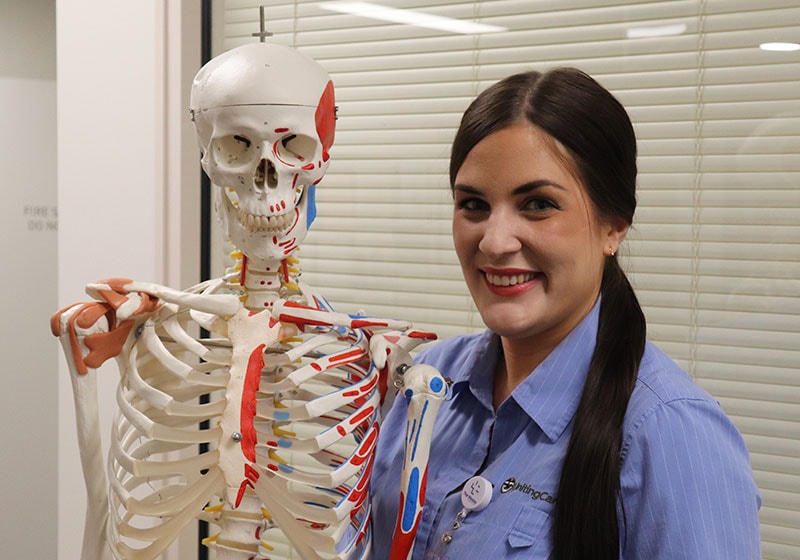 The Wesley Hospital Orthopaedic Nurse smiling at camera standing next to educational skeletal frame