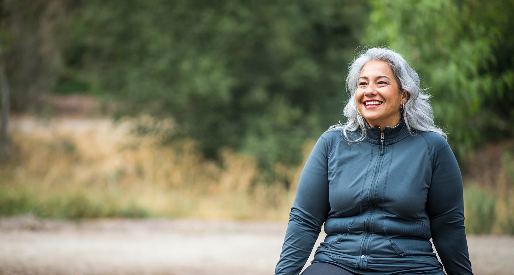A woman in a exercise jacket smiling outdoors