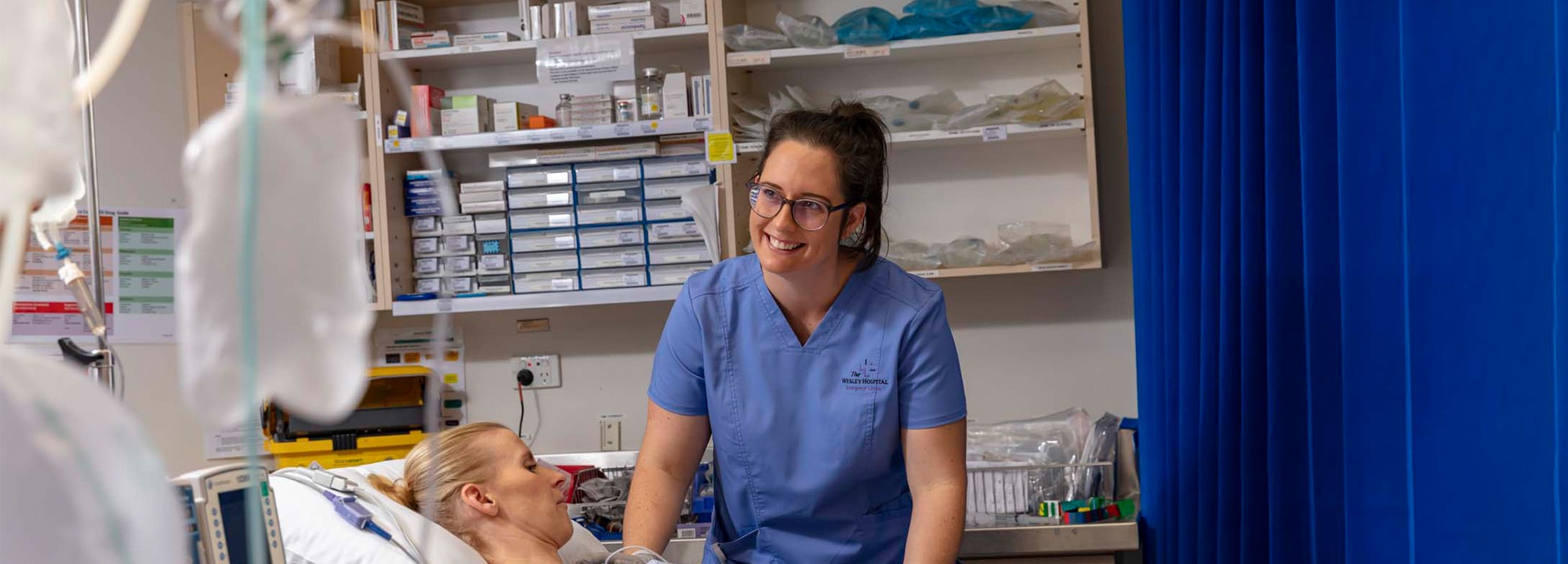Wesley hospital nurse standing at bedside smiling