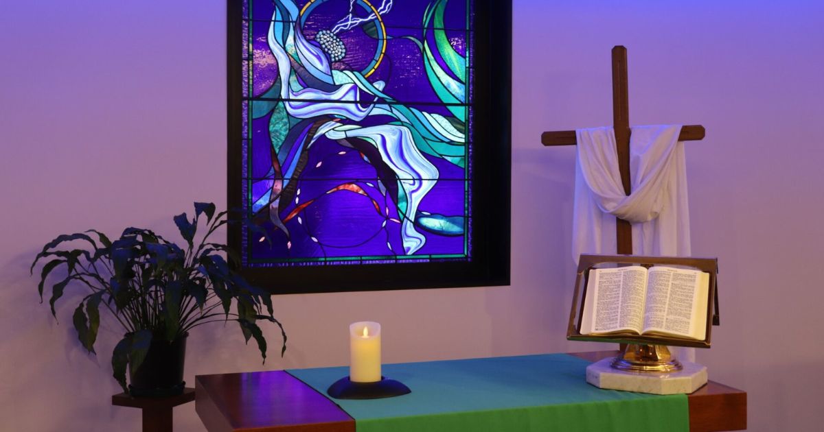 The Wesley Hospital Chapel's stained glass window with a candle, cross and bible in the foreground.