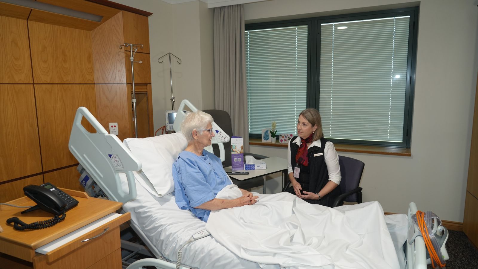 A Wesley Hospital chaplain sits at the bedside of a patient.