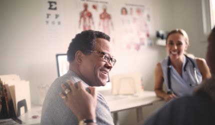 A smiling patient talks to a doctor.
