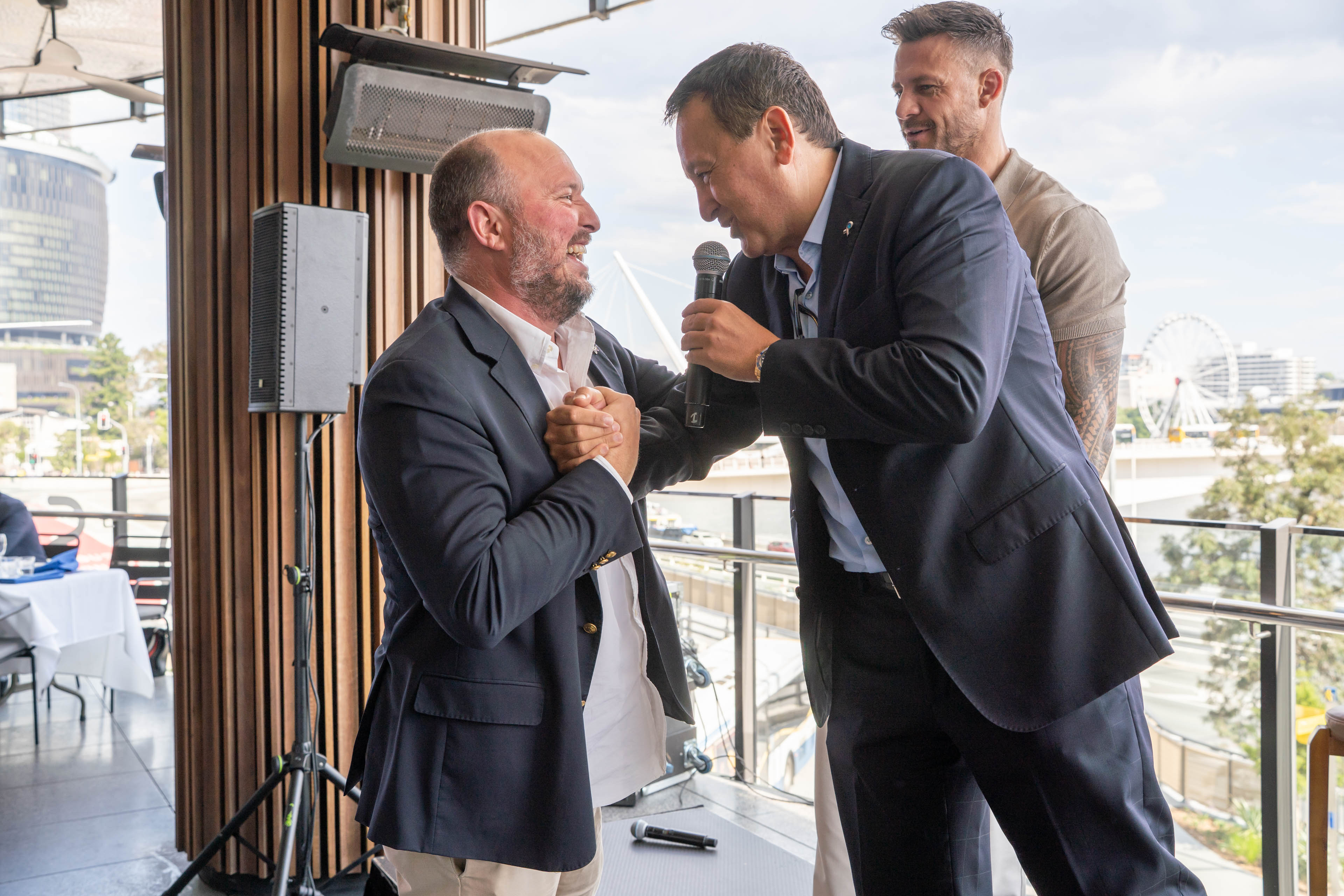 John Gambaro shakes hands with a stakeholder while presenting at the 2025 Gambaro Lunch.