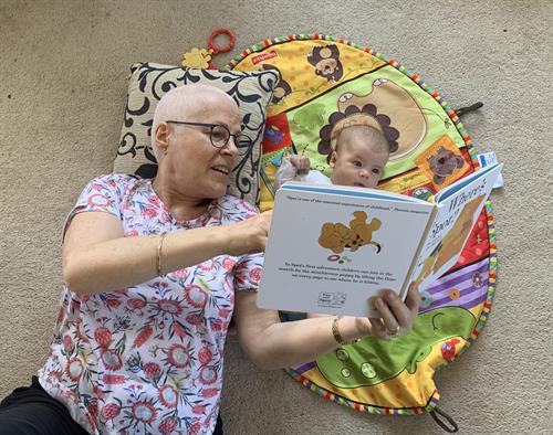 A lady reading a picture book to a child