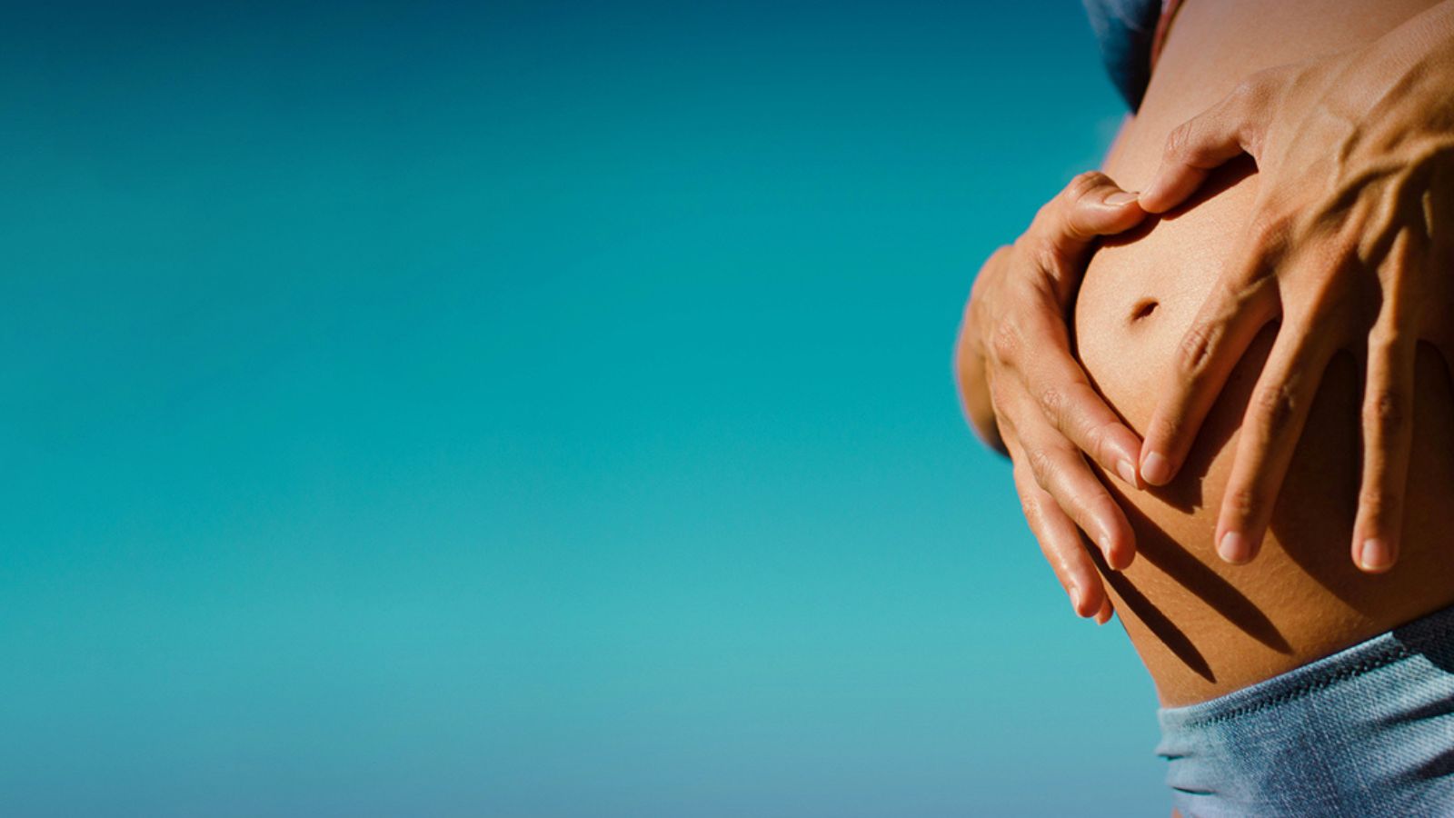 Hands holding a pregnant belly.