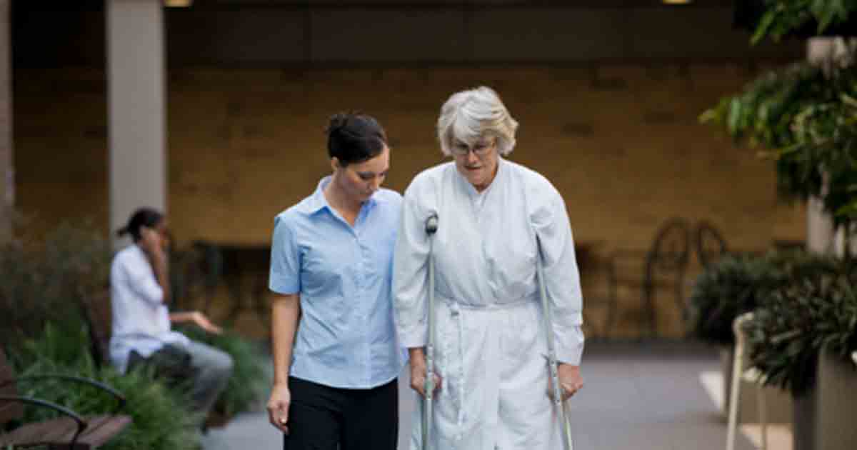 The Wesley Hospital staff member assisting older lady walking on crutches.