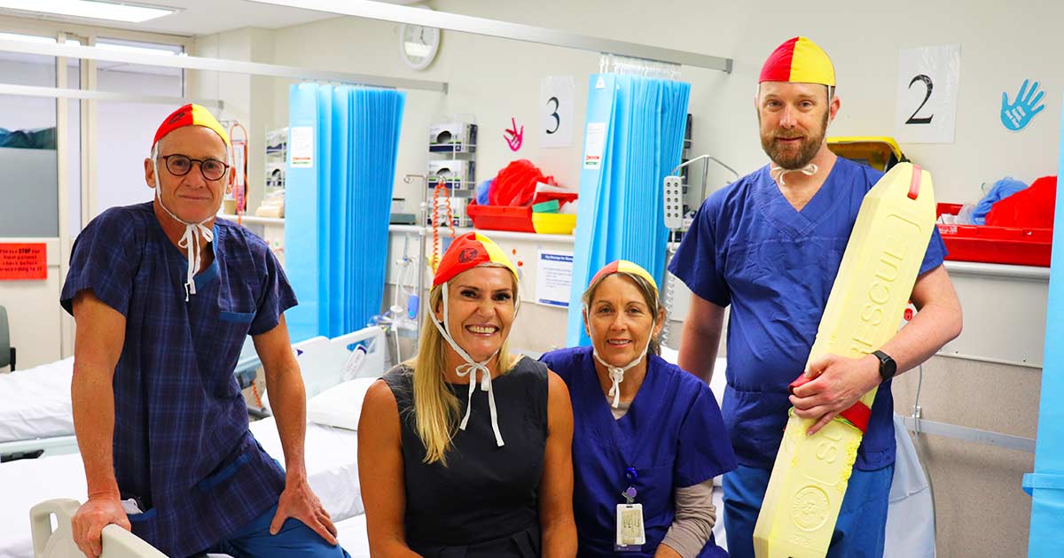 Surgeon Dr Ian Martin, Dietitian Annalie Houston, Pre-Admission Nurse Sharon Finucan and Clinical Nurse Ben Crothers dressing in swimming costumes in hospital smiling at camera
